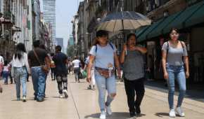 Ciudadanos intentan mitigar el calor con sombrillas y tomando agua